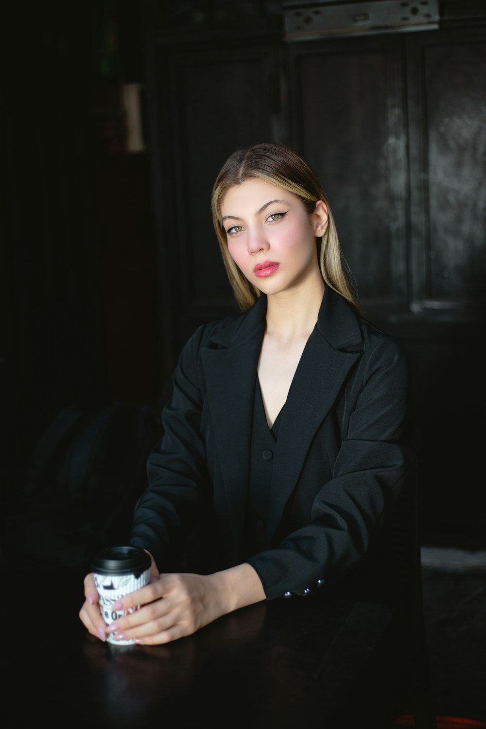 a woman sitting at a table with a drink in her hand