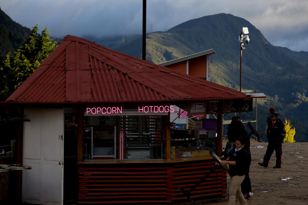 a woman is standing outside of a hot dog stand