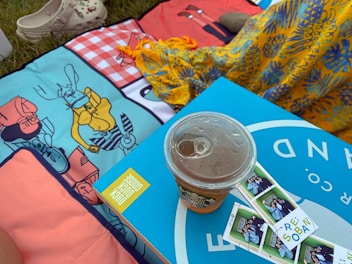 A beautifully patterned collapsible nylon picnic mat spread on a grassy field.