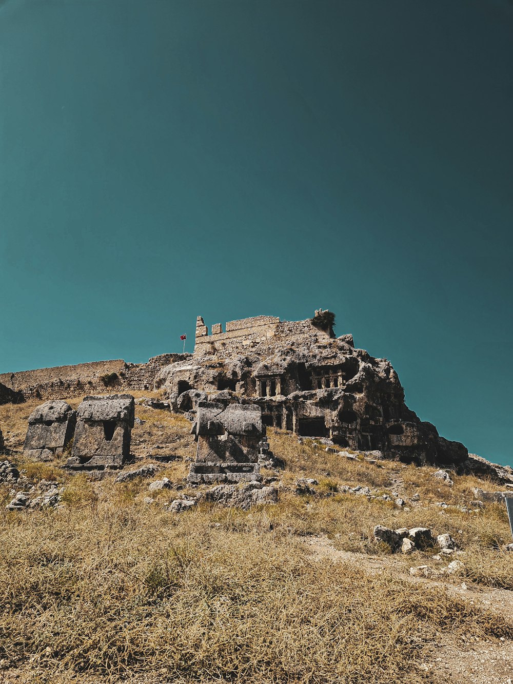 a large rock formation sitting on top of a dry grass covered hillside