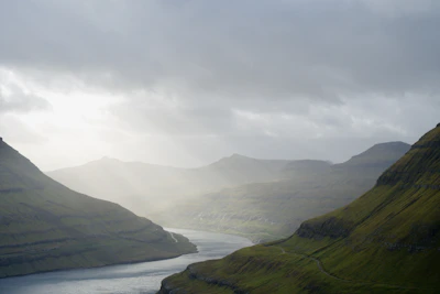 Lush green mountain valley with a winding river at dawn.