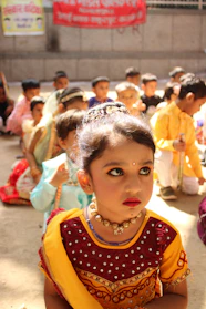 A cheerful child dressed in a colorful Bollywood costume with traditional accessories and a joyful smile.
