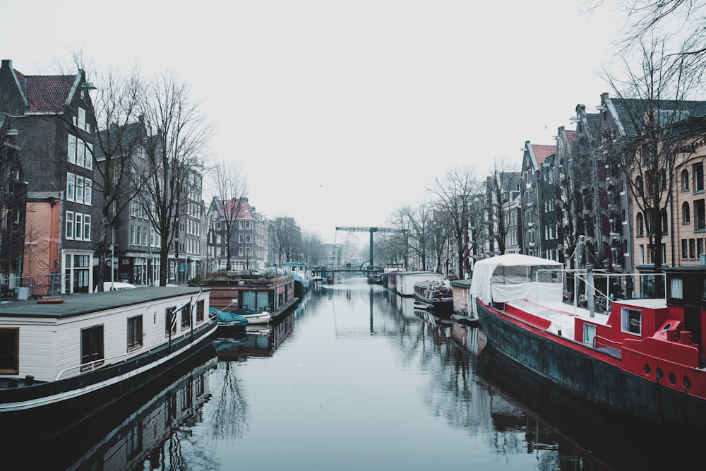 a canal filled with lots of boats next to tall buildings