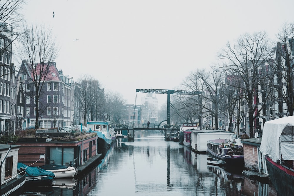 a canal filled with lots of boats next to tall buildings