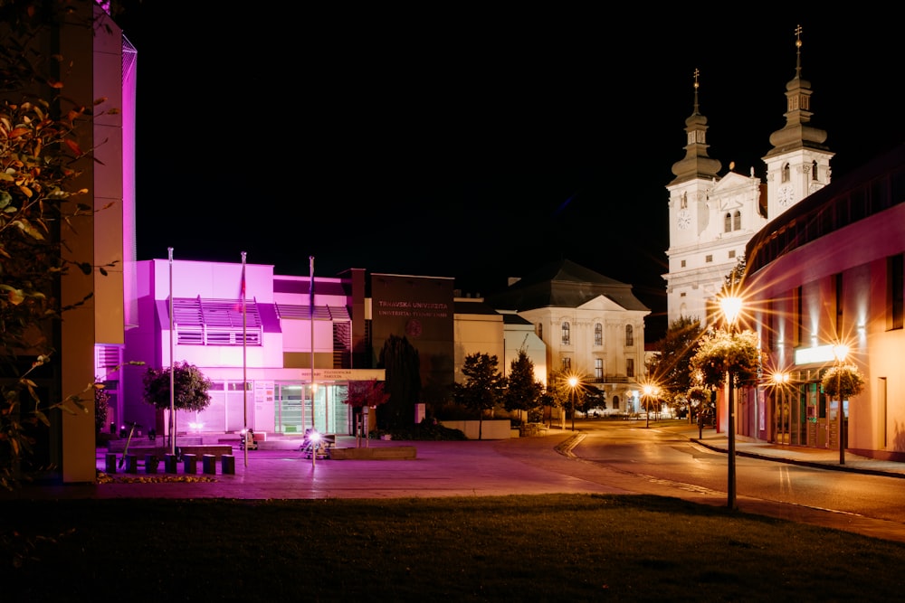 Una strada cittadina di notte con una chiesa sullo sfondo