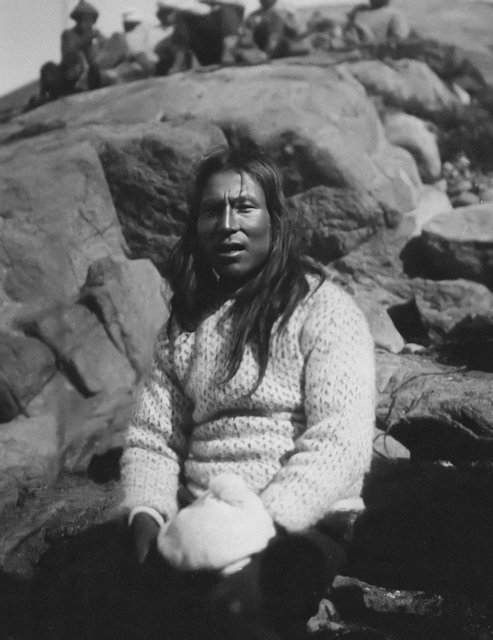 an old photo of a woman sitting on rocks
