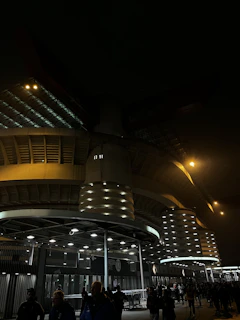 Wide shot of the Emilio Roto stadium lit up at night with fans entering.