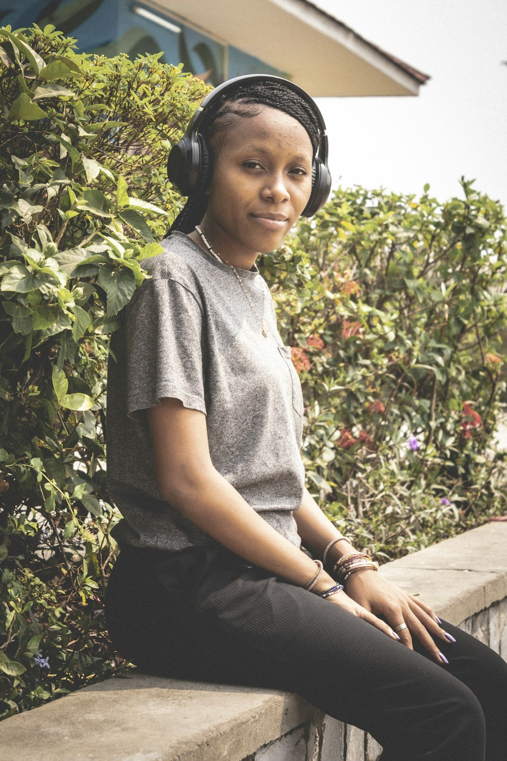 a woman wearing headphones sitting on a ledge
