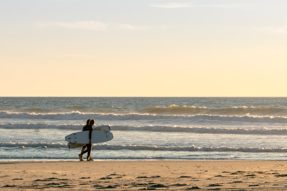 a person holding a surf board on a beach