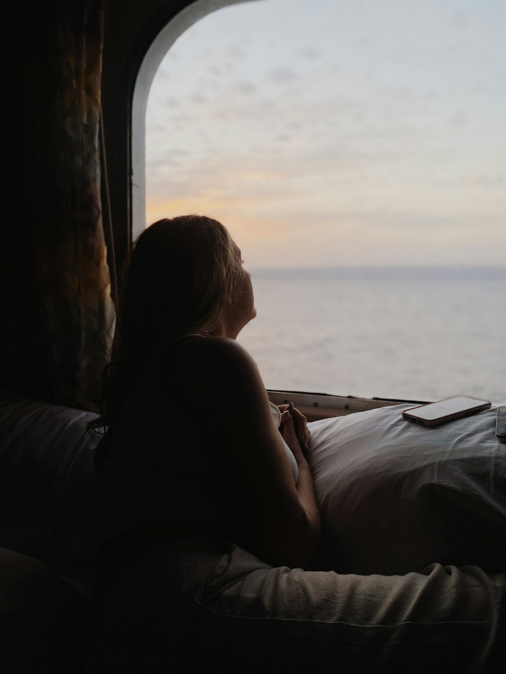 a woman sitting on a bed looking out a window