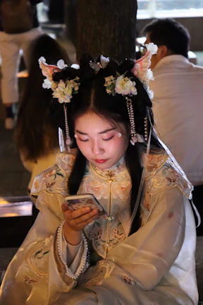A young Indonesian woman happily practicing Japanese phrases on her smartphone in a cozy room.