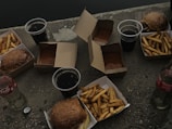 A variety of burritos and burgers arranged on a picnic table ready to eat.