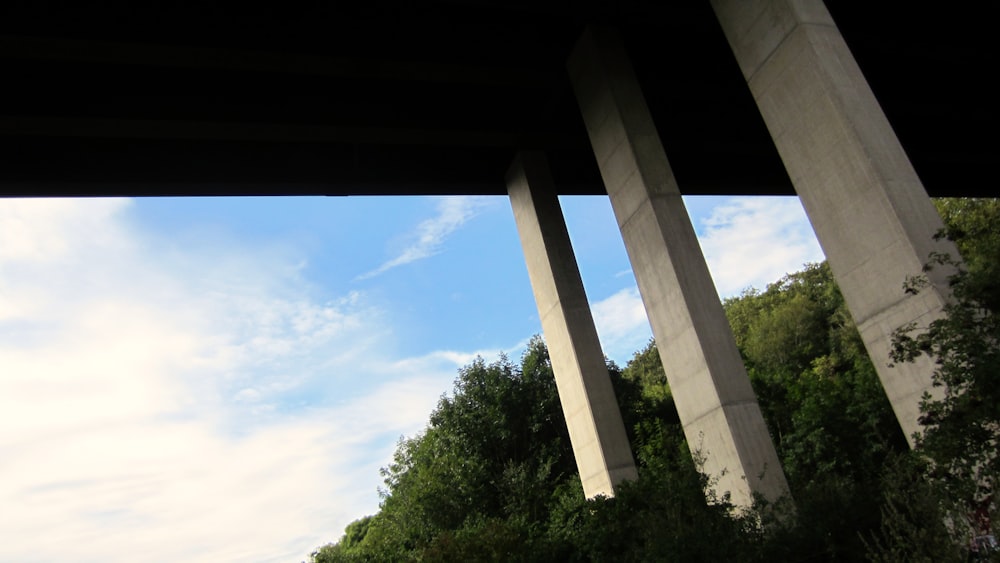 a view of the underside of a bridge with trees in the background