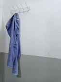 Artistic shot of denim jeans hanging on a minimalist rack against a white wall.