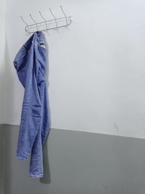 A pair of classic blue jeans displayed on a mannequin against a brick wall.