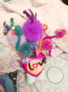 Brightly colored mugs and pens displayed together on a shelf.