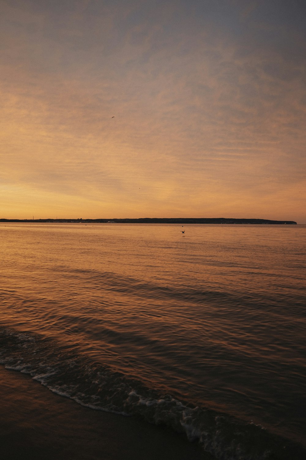 the sun is setting over the water at the beach