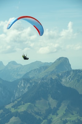 a paraglider in the air over a mountain range