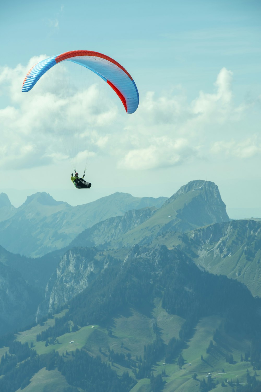 a paraglider in the air over a mountain range