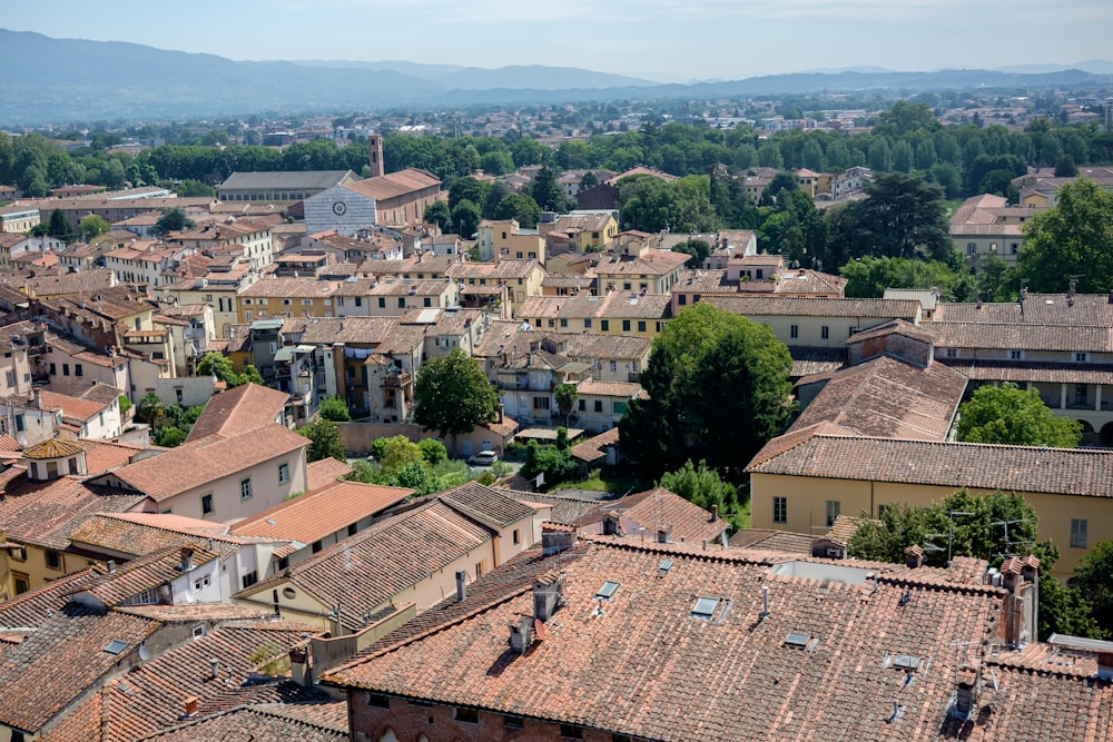 an aerial view of a city with rooftops and mountains in the background