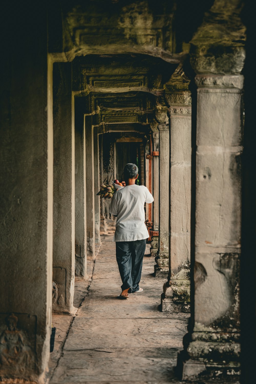 a man walking down a long hallway between two buildings