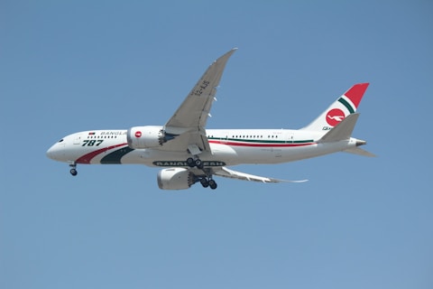 A large commercial airplane with the Biman Bangladesh airlines livery on a clear day. The aircraft is in mid-flight, showcasing its sleek design and the airline's distinctive red and green logo on the tail.