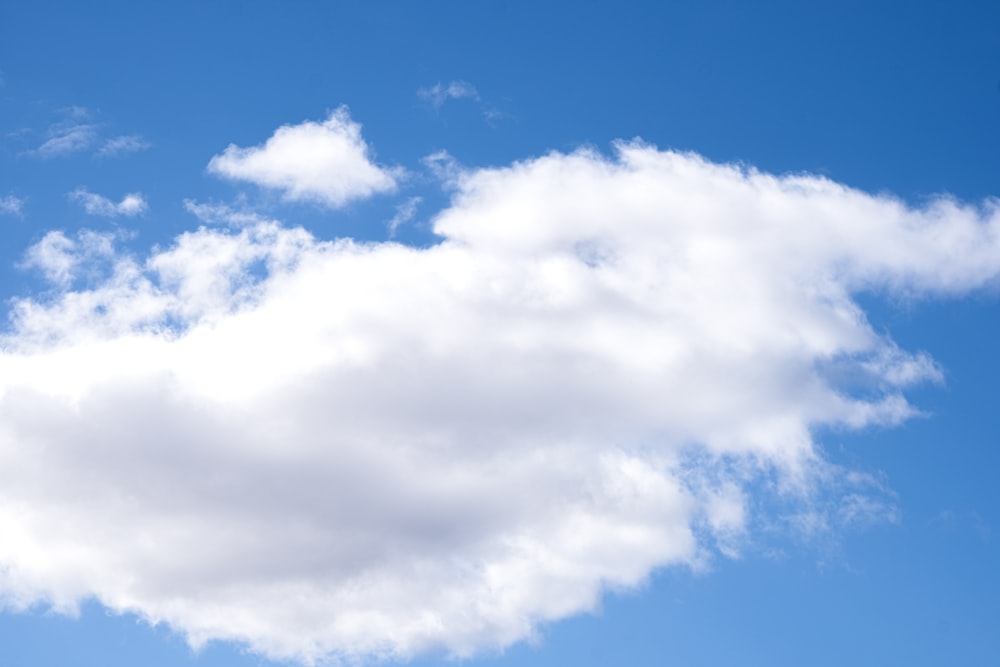 a plane flying in the sky with a cloud in the background