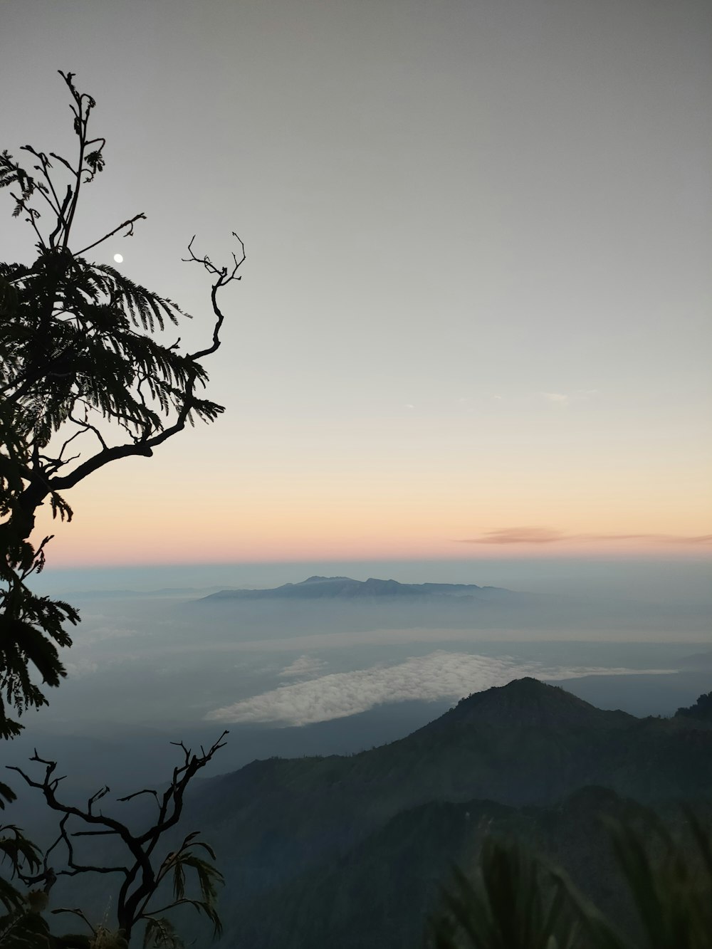 a view of the mountains and clouds from the top of a hill