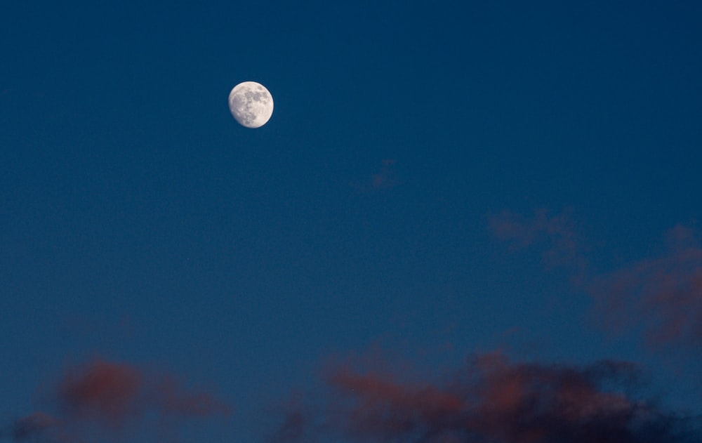 a full moon in a blue sky with clouds