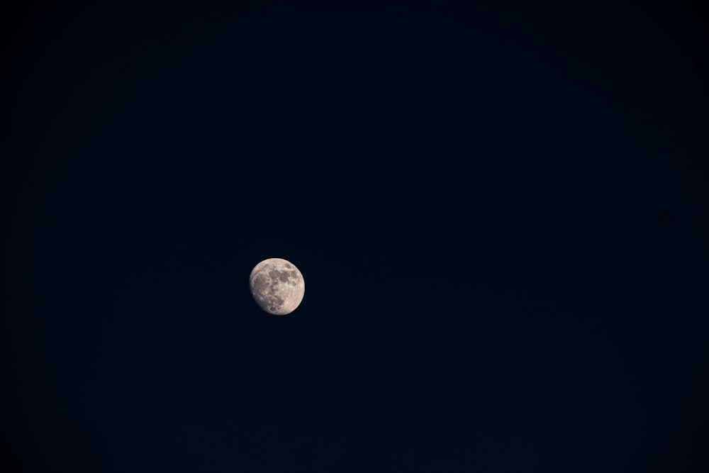 a full moon is seen in the dark sky