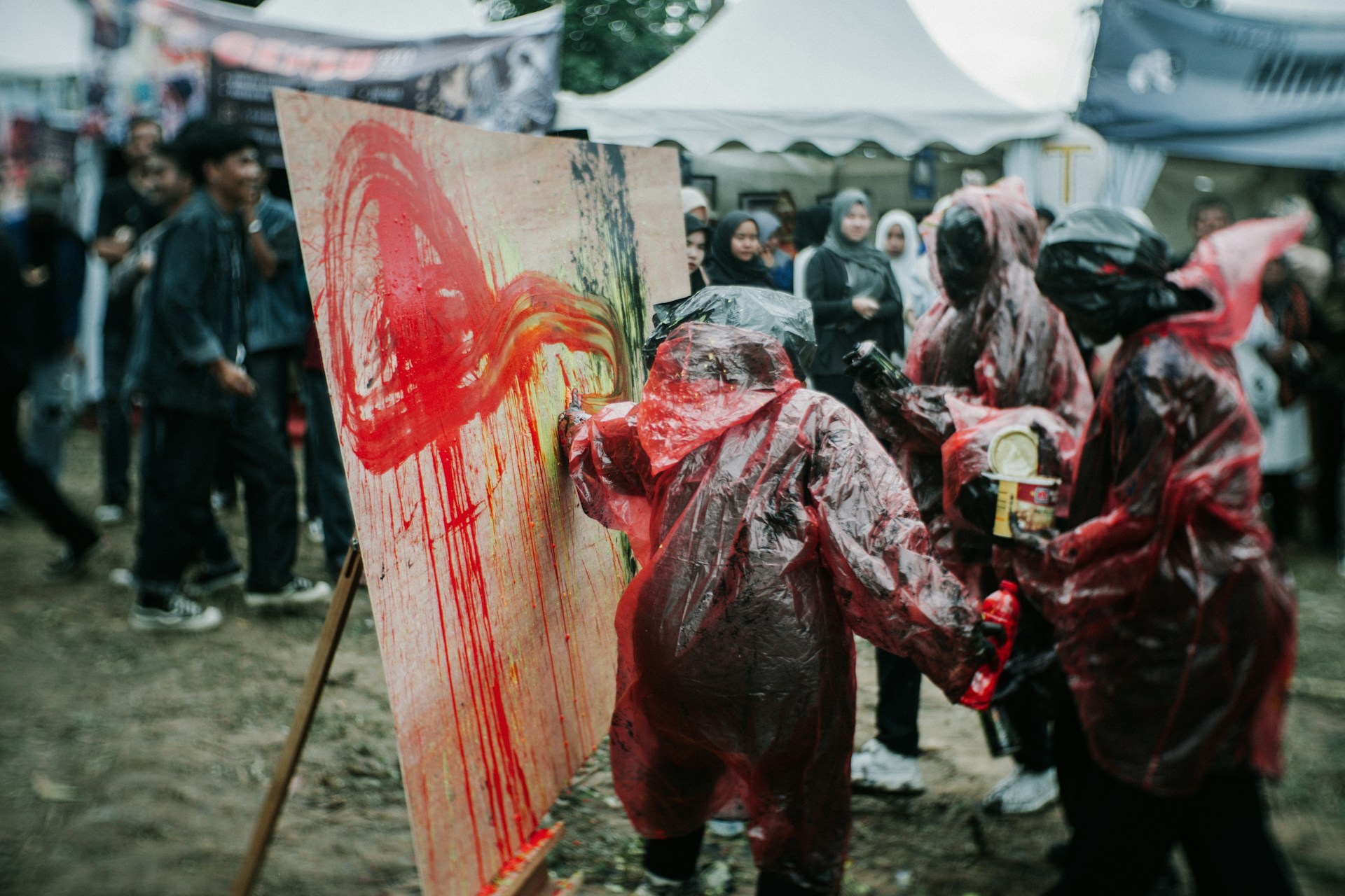 Participants collaborating on a large outdoor mural, blending natural elements with colorful paint under an open sky.