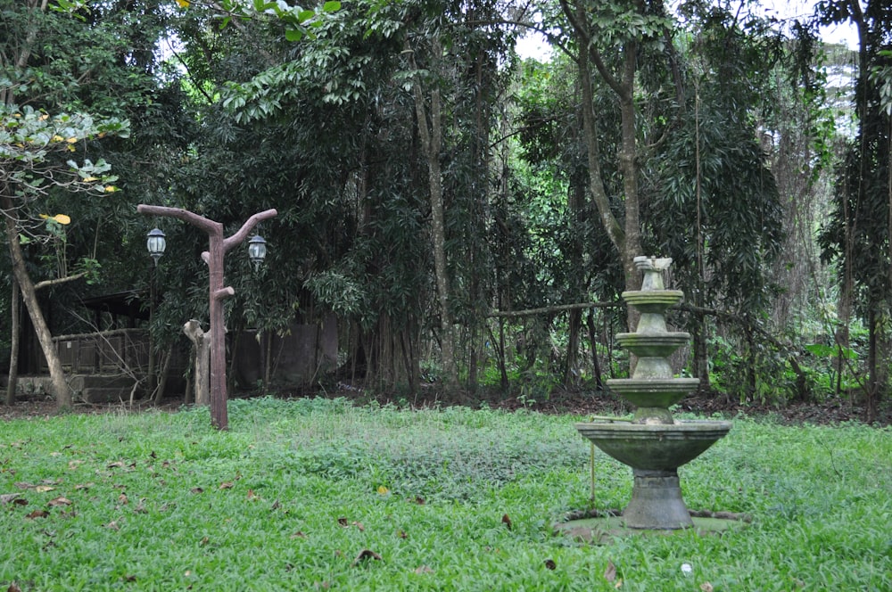 a stone fountain in the middle of a grassy area