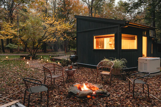 a small cabin in the woods with a fire pit