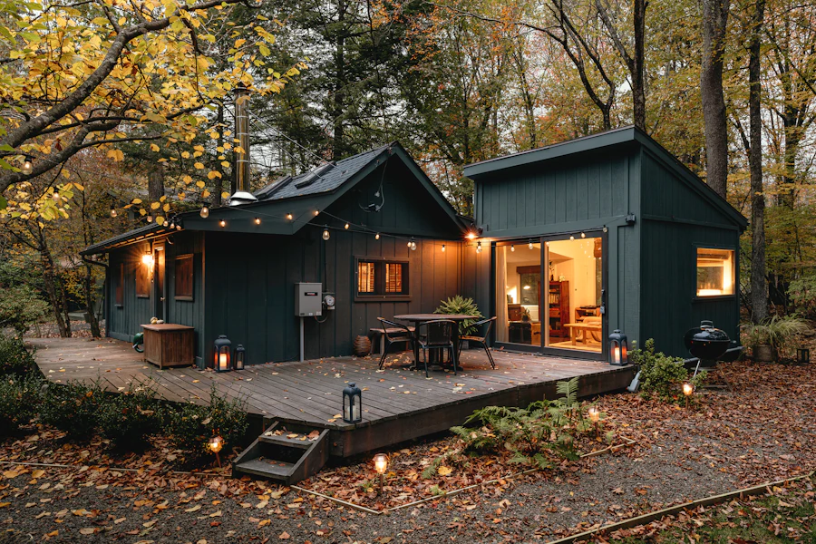 Two dark timber cabins with a lit deck at dusk