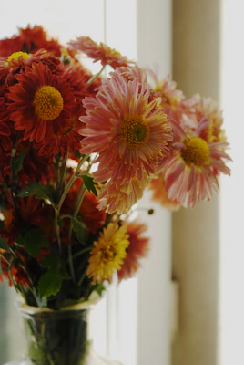 A vibrant bouquet of mixed seasonal flowers in a rustic vase, glowing softly in natural light.