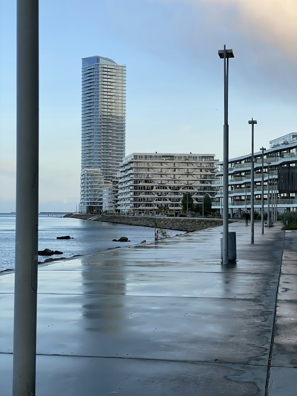 a wet sidewalk next to a body of water