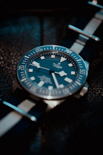 Vintage Omega Speedmaster with a classic black bezel displayed against a dark navy background with soft lighting