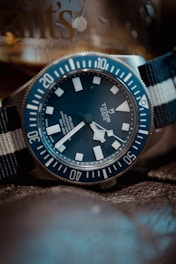 a blue and white watch sitting on top of a bed