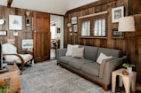 a living room with wood paneling and a gray couch