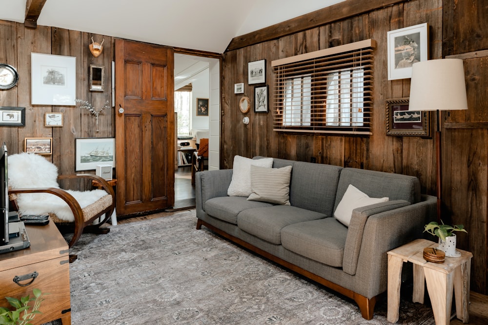 a living room with wood paneling and a gray couch