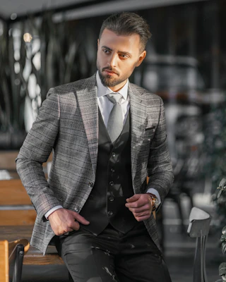 A stylish man wearing a sharp blazer and crisp shirt, standing confidently in an urban setting.