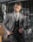 A well-dressed man wearing a tailored blazer over a casual shirt, standing confidently in an urban setting.