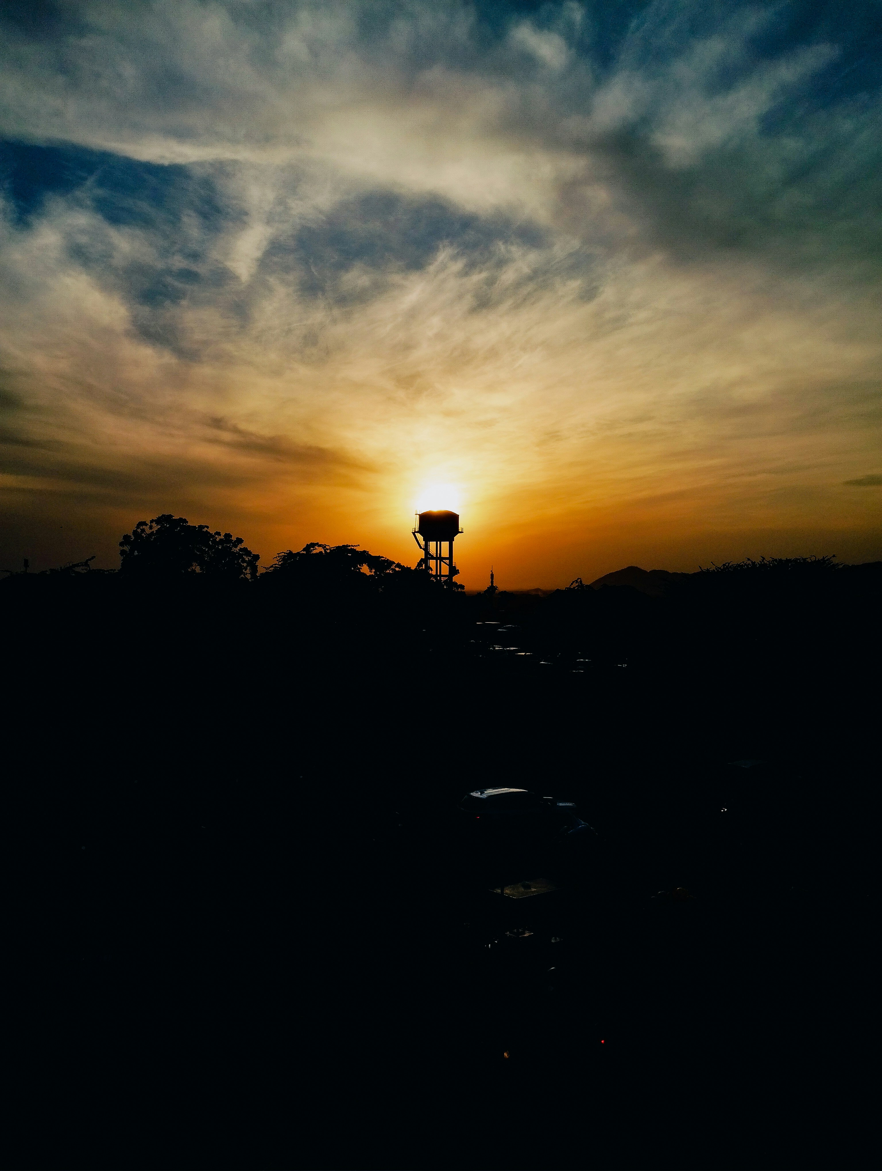 a sunset with a water tower in the distance