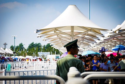 Large temporary canopy covering an outdoor event with people enjoying underneath.