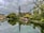 a boat floating down a river next to a lush green forest