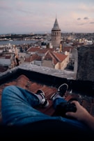 An urban rooftop view at dusk, with a traveler enjoying the city lights and skyline from a quiet perch.