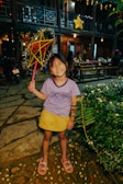 A smiling child holding up a handmade pastel-colored paper star.