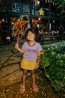 A joyful child in a festive green outfit playing with lanterns decorated for Ramadan.
