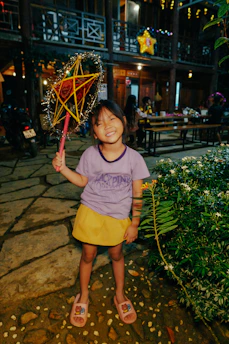 A joyful child holding a glowing lantern in a dim forest, symbolizing resilience and inner strength.