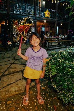 A smiling child holding up a handmade pastel-colored paper star.
